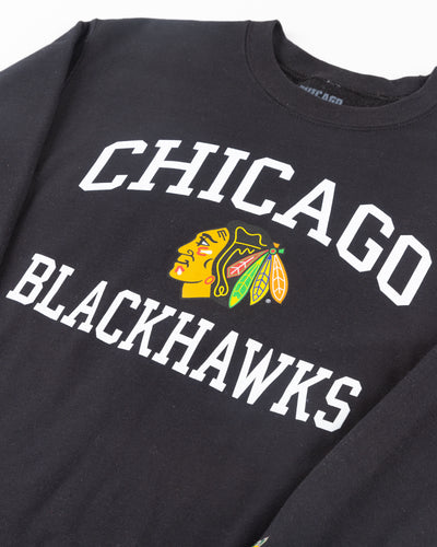 black Chicago Blackhawks crewneck with wordmark and primary logo on chest and secondary logo on left wrist - detail front lay flat