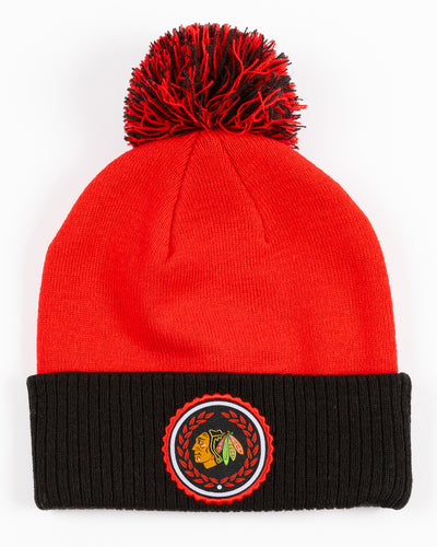 red and black adidas knit pom hat with Chicago Blackhawks primary logo collegiate inspired patch on cuff - front lay flat