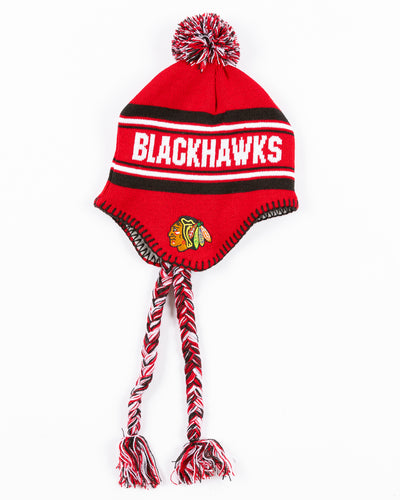 red youth knit hat with tassels and Chicago Blackhawks wordmark on front and Chicago Blackhawks primary logo and NHL logo embroidered on sides - side lay flat