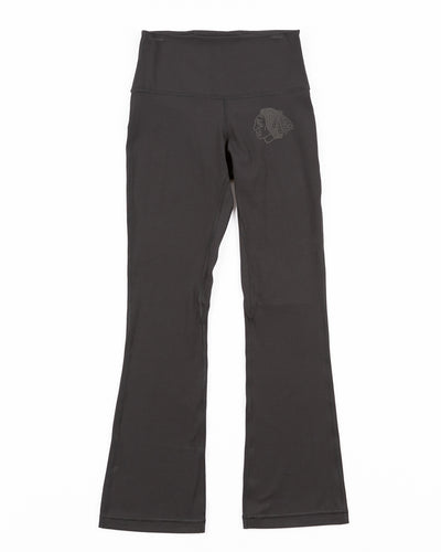 black lululemon yoga pants with subtle flare at hem and tonal Chicago Blackhawks primary logo printed on left leg - front lay flat