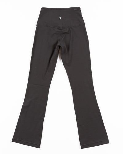 black lululemon yoga pants with subtle flare at hem and tonal Chicago Blackhawks primary logo printed on left leg - back lay flat