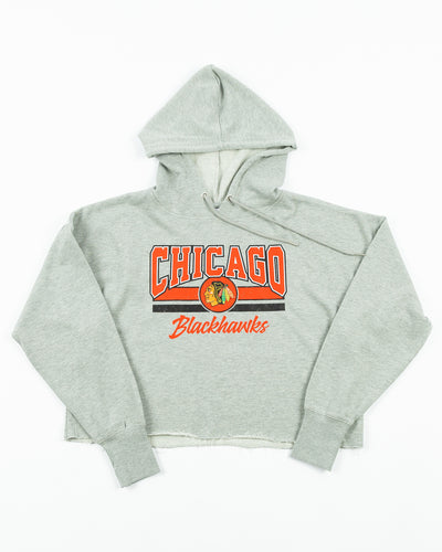 grey cropped ladies hoodie with Chicago Blackhawks wordmark and primary logo graphic across the front - front lay flat