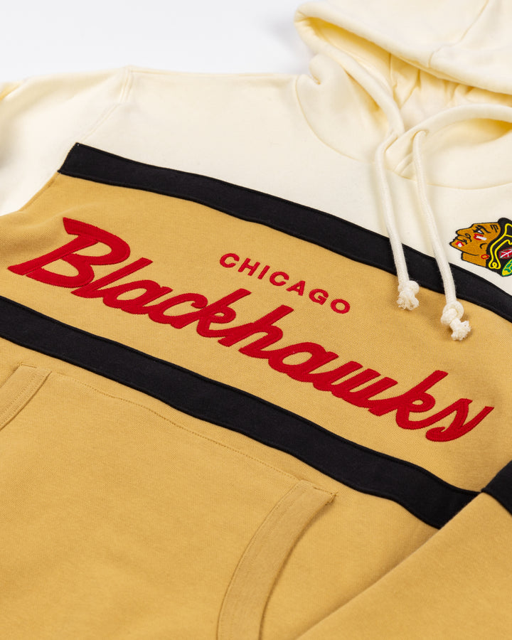 cream and tan Mitchell & Ness hoodie with Chicago Blackhawks wordmark and primary logo on front - front detail lay flat