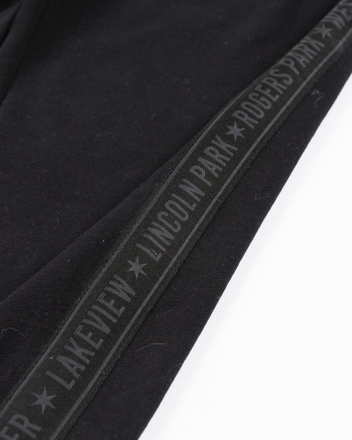 black sweatpants with Chicago Blackhawks secondary logo embroidered in Chicago flag colorway on left thigh and Chicago neighborhood names down sides - detail lay flat