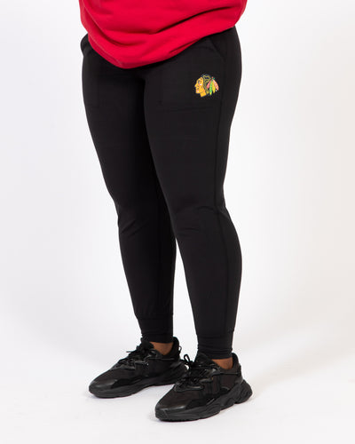 black lululemon women's jogger with full color Chicago Blackhawks primary logo on left leg - close up on model