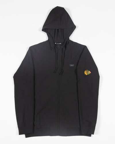 black TravisMathew zip up hoodie with embroidered Chicago Blackhawks primary logo on left shoulder - front lay flat