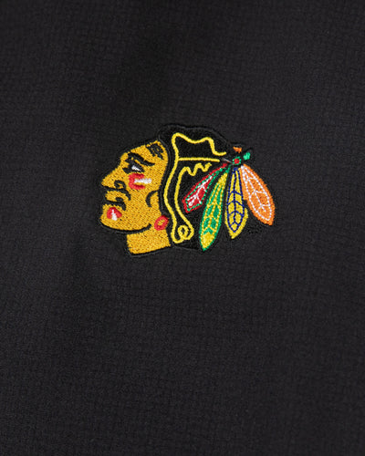 black TravisMathew zip up hoodie with embroidered Chicago Blackhawks primary logo on left shoulder - detail lay flat