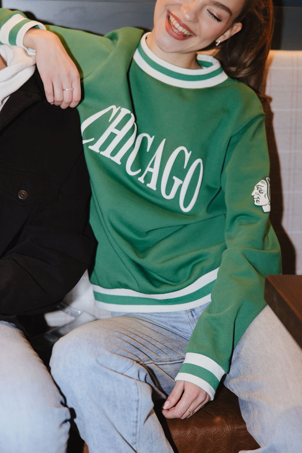 woman wearing green Alice & Wonder crewneck sweater with Chicago wordmark graphic and tonal Chicago Blackhawks primary logo on left shoulder