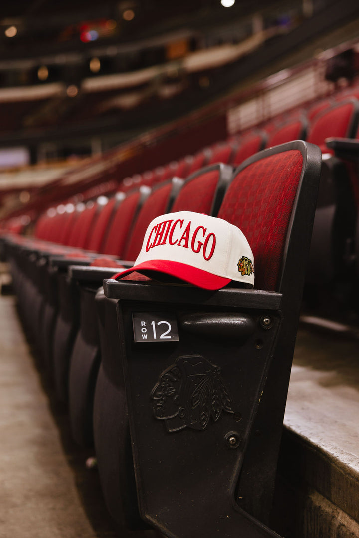 cream and red Alice & Wonder hat with Chicago wordmark on front and Chicago Blackhawks primary logo on left side on seats inside the United Center