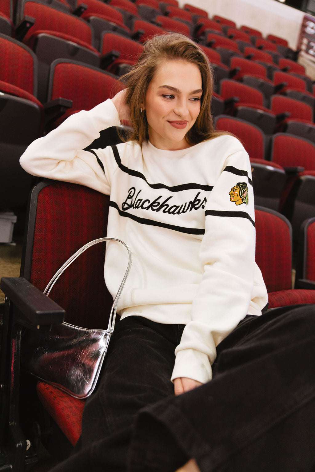 woman wearing Alice & Wonder cream crewneck sweater with Blackhawks script graphic on front and Chicago Blackhawks primary logo on left shoulder