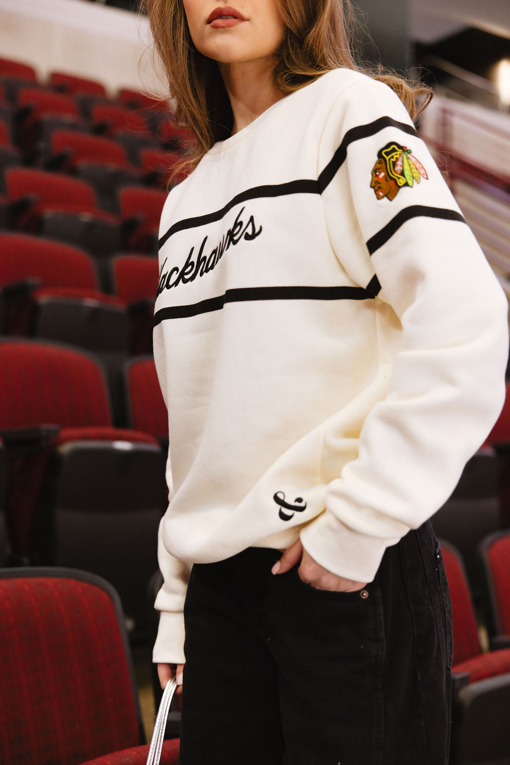 woman wearing Alice & Wonder cream crewneck sweater with Blackhawks script graphic on front and Chicago Blackhawks primary logo on left shoulder