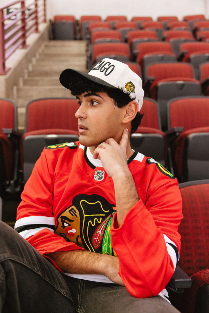 man wearing cream and black Alice & Wonder hat with Chicago wordmark on front and Chicago Blackhawks primary logo on left side