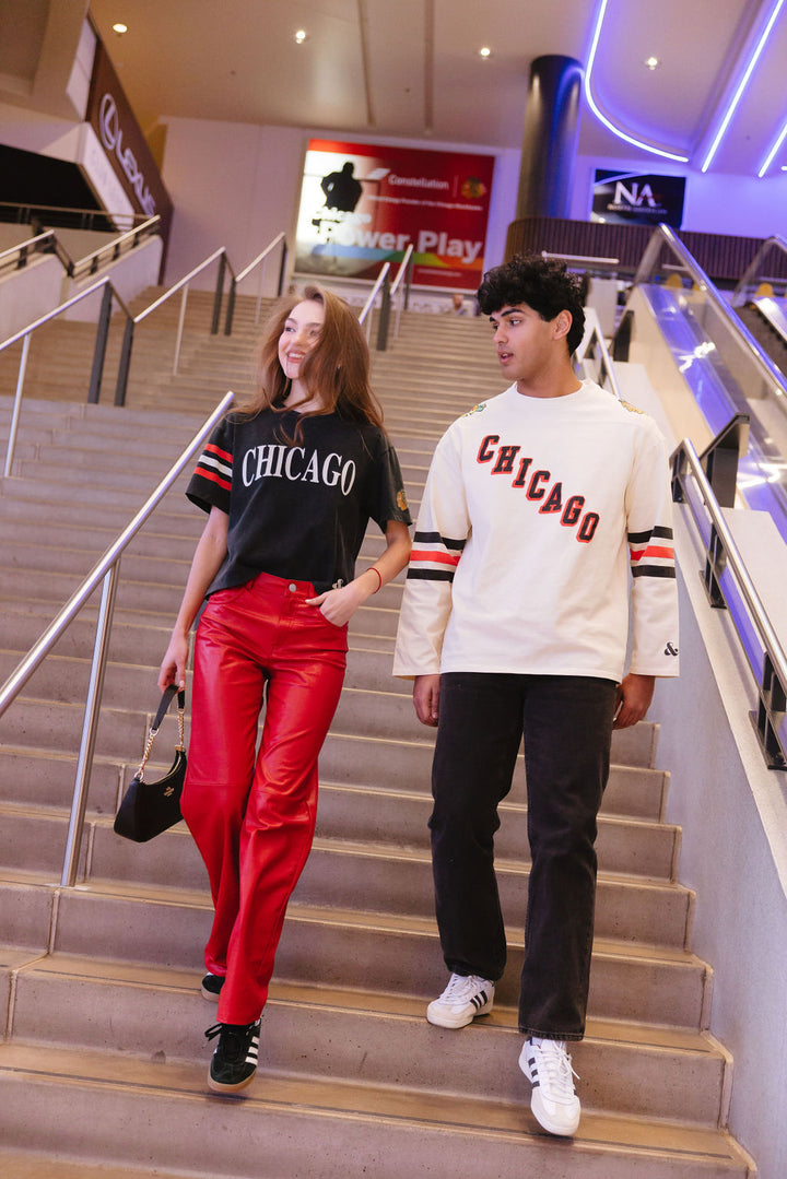 man wearing cream Alice & Wonder long sleeve tee with diagonal Chicago wordmark graphic and Chicago Blackhawks secondary and primary logo on shoulders with jersey stripes on sleeves