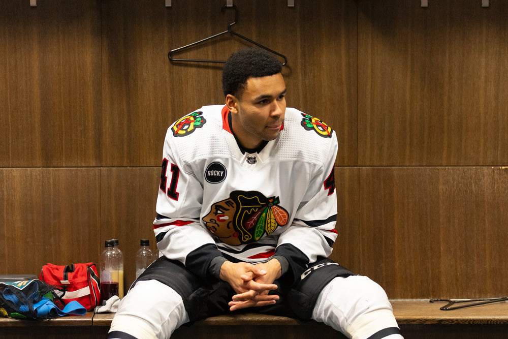 Isaak Phillips in white Chicago Blackhawks adidas away jersey in locker room at Edmonton