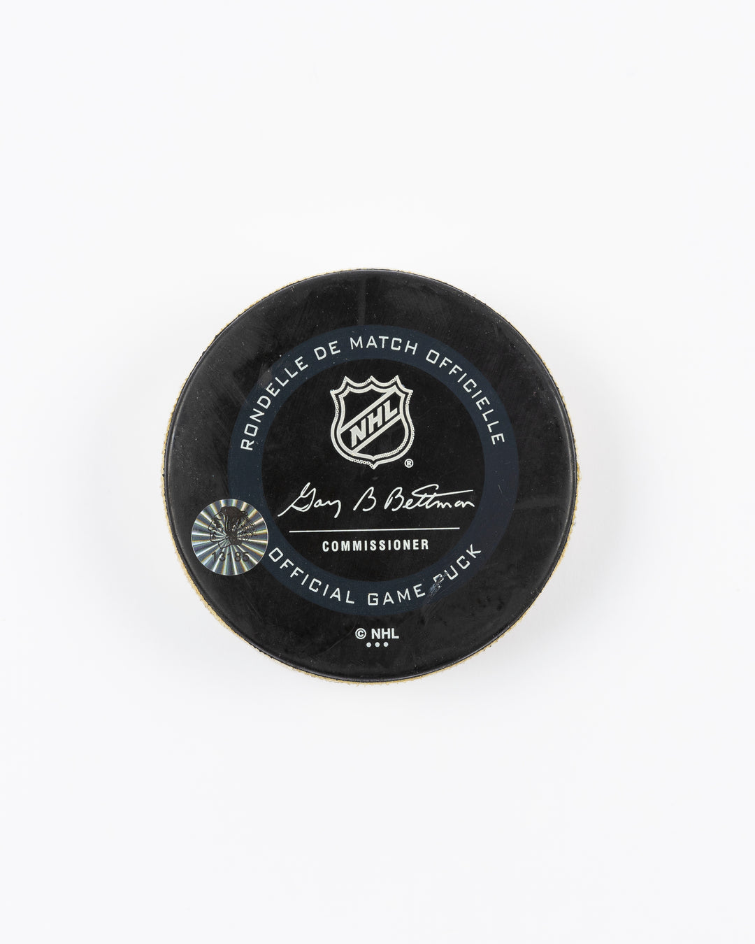 game-used hockey goal puck shot by former Chicago Blackhawks player Alex DeBrincat - back lay flat