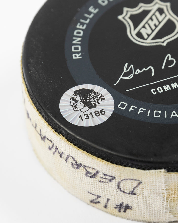 game-used hockey goal puck shot by former Chicago Blackhawks player Alex DeBrincat - hologram sticker detail lay flat