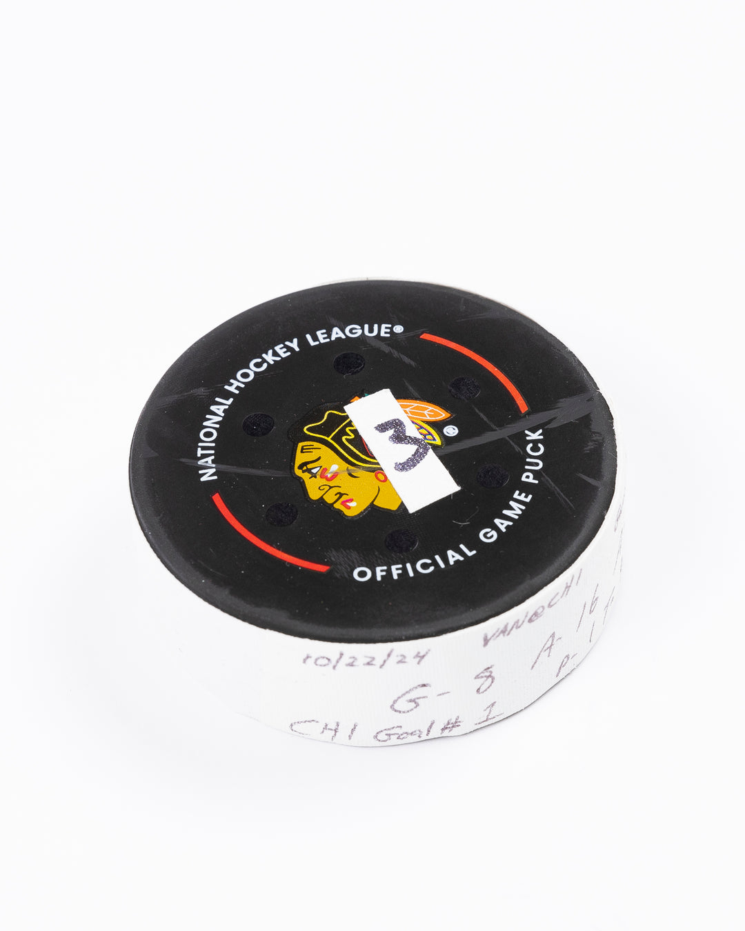 game used hockey goal puck scored by Chicago Blackhawks player Ryan Donato during game on October 22, 2024 - front angled lay flat