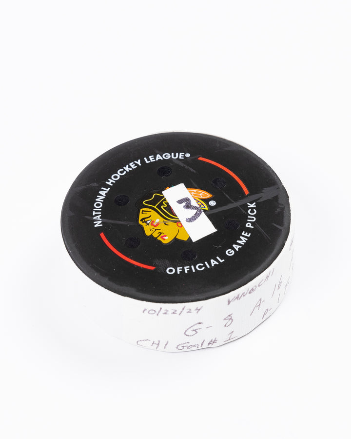 game used hockey goal puck scored by Chicago Blackhawks player Ryan Donato during game on October 22, 2024 - front angled lay flat