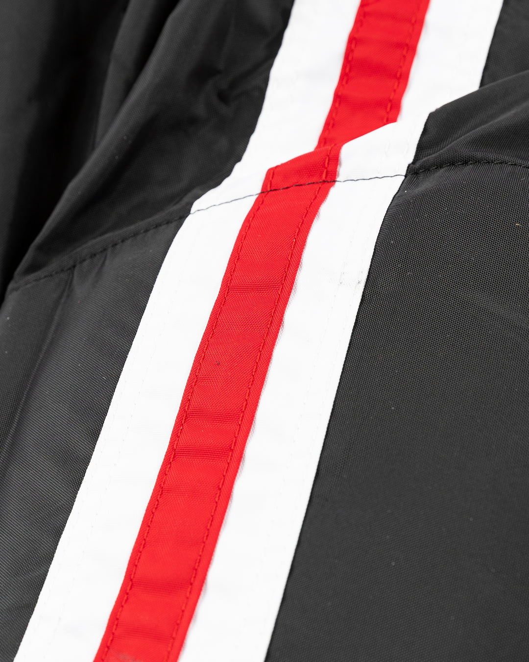 black CCM hockey pants used by unspecified Chicago Blackhawks player - stripe detail lay flat