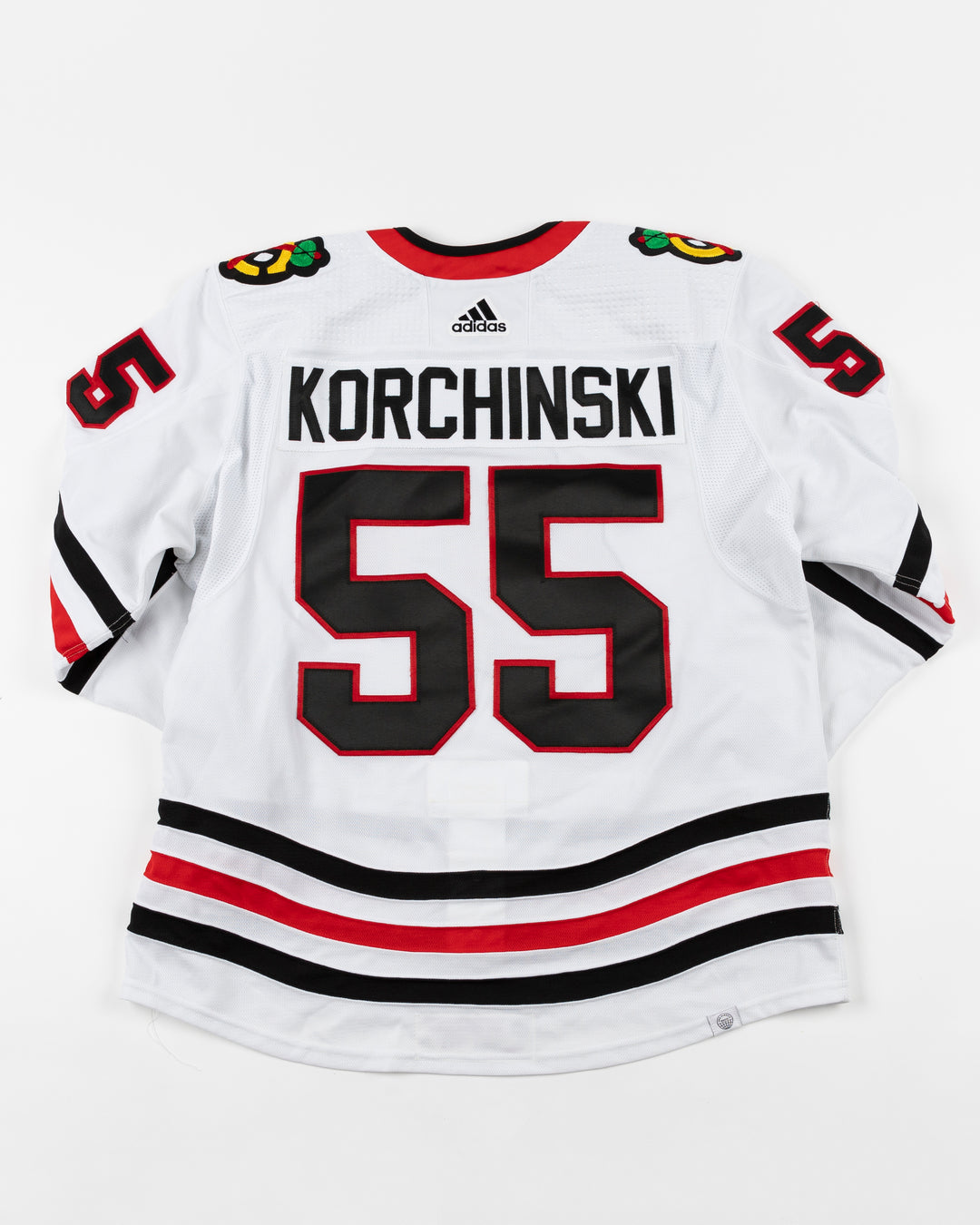 white adidas Chicago Blackhawks away jersey game used by Kevin Korchinski - back lay flat