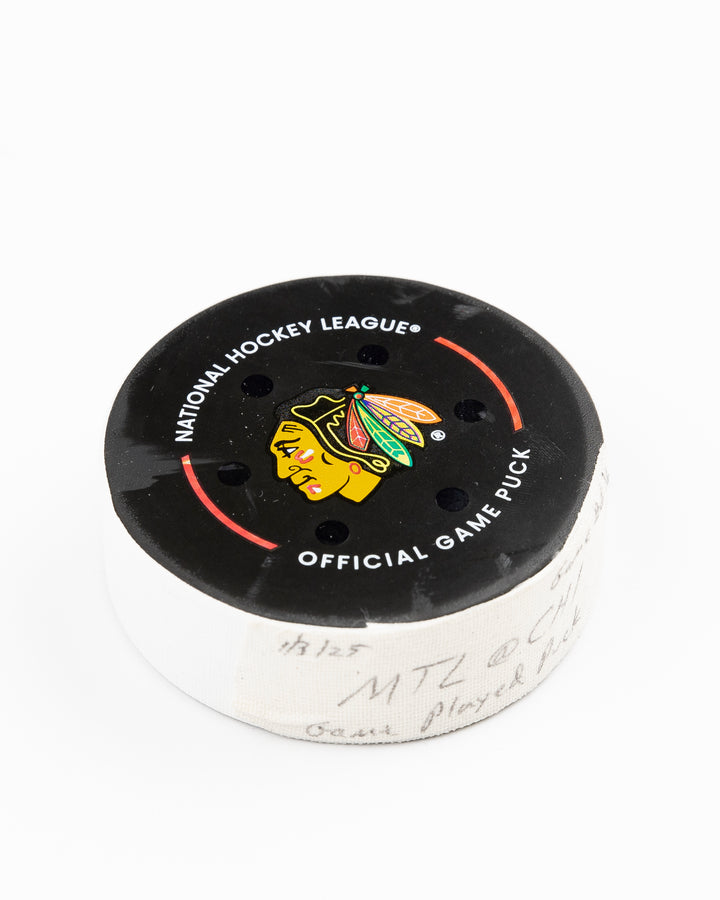 official Chicago Blackhawks game-used hockey puck used in the game against the Montreal Canadiens on January 3, 2025 - front angle lay flat