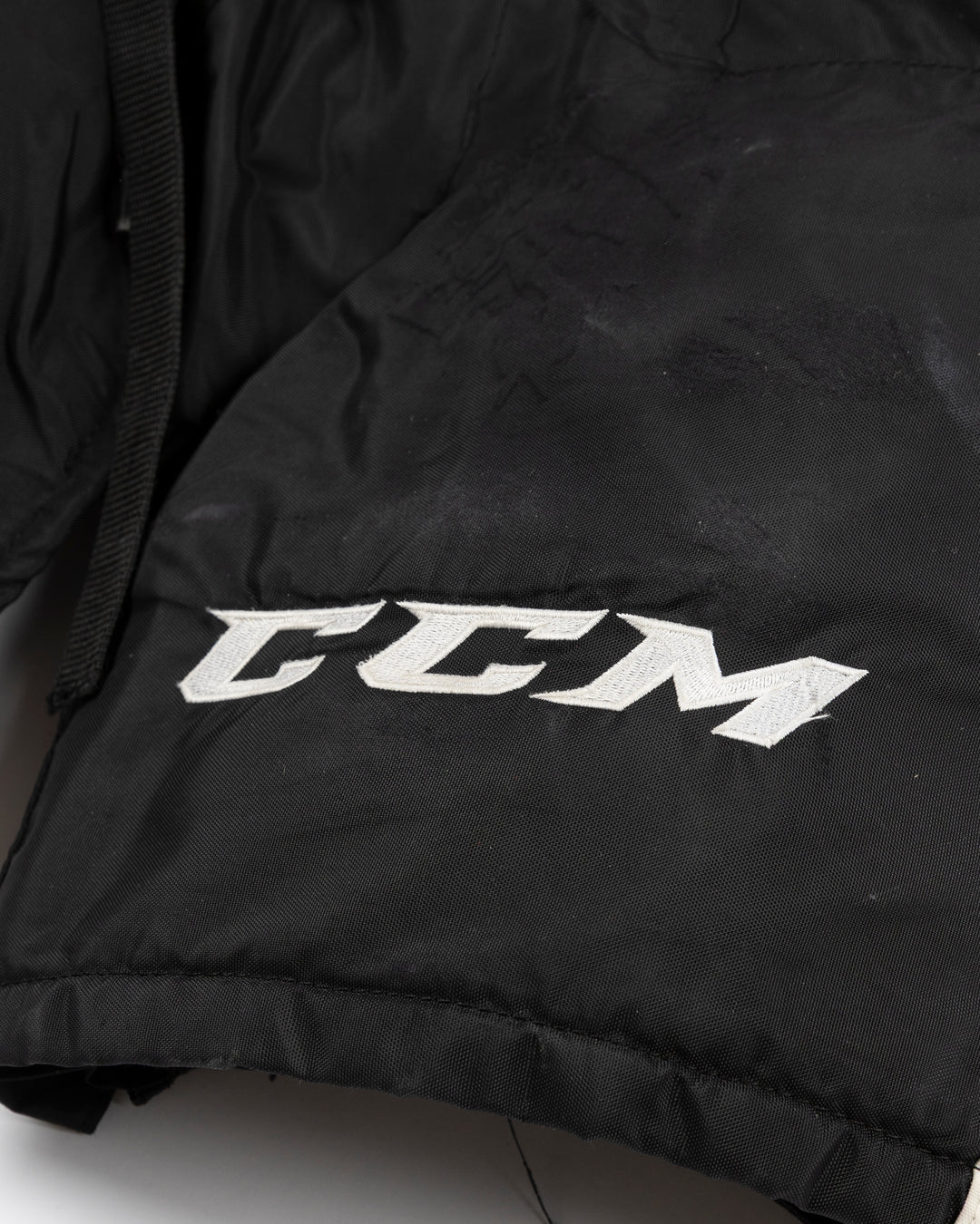 black CCM hockey pants used by Chicago Blackhawks player Wyatt Kaiser - logo detail lay flat