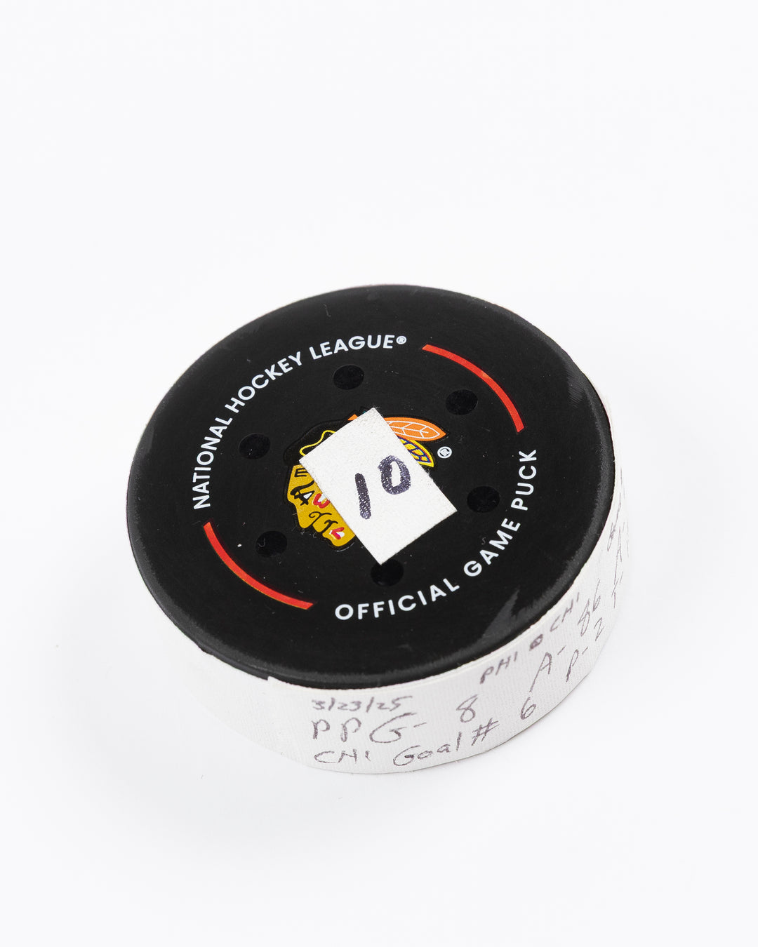 official hockey goal puck scored by Chicago Blackhawks player Ryan Donato on 3/23/25 - front angle lay flat