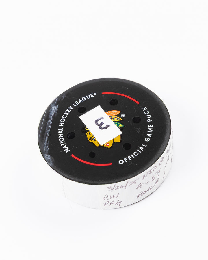 official hockey goal puck used by Chicago Blackhawks player Tyler Bertuzzi on 3/26/25 - front angle lay flat