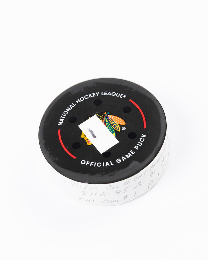 official hockey goal puck scored by Chicago Blackhawks player Ilya Mikheyev on 4/2/25 - front angle lay flat