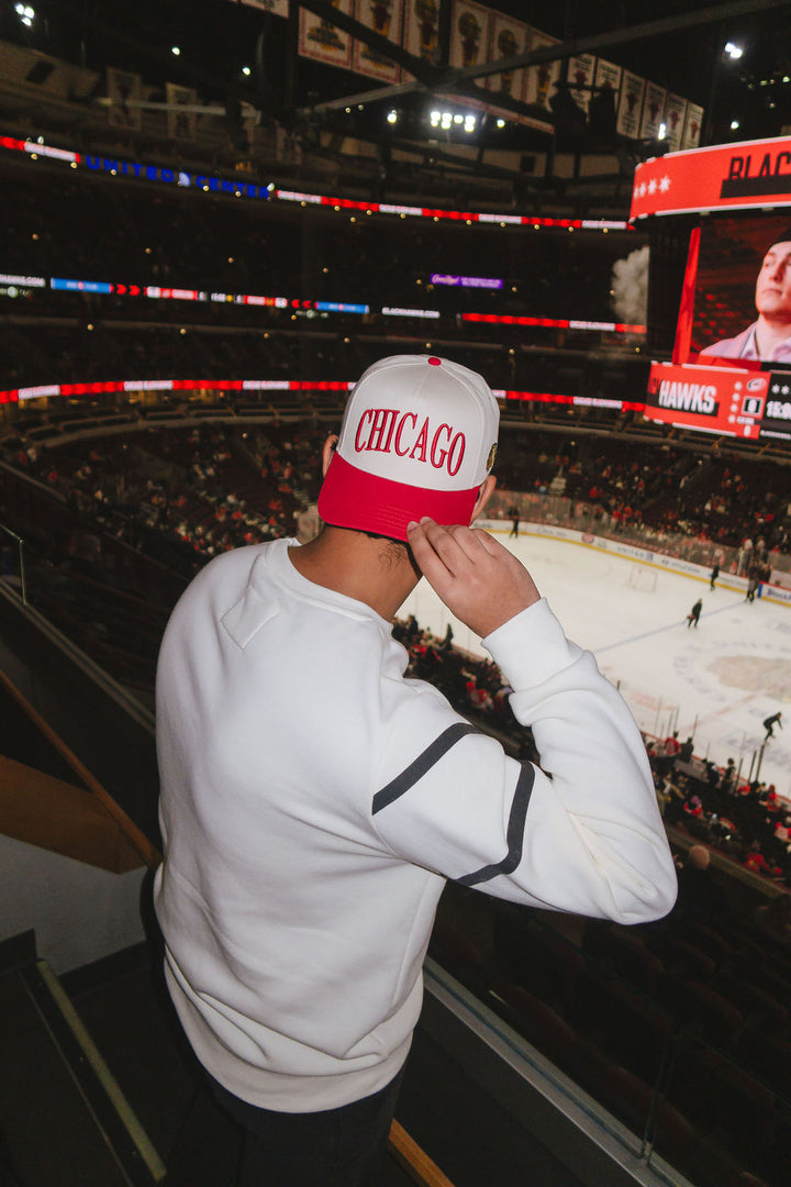 man wearing cream and red Alice & Wonder hat with Chicago wordmark on front and Chicago Blackhawks primary logo on left side 