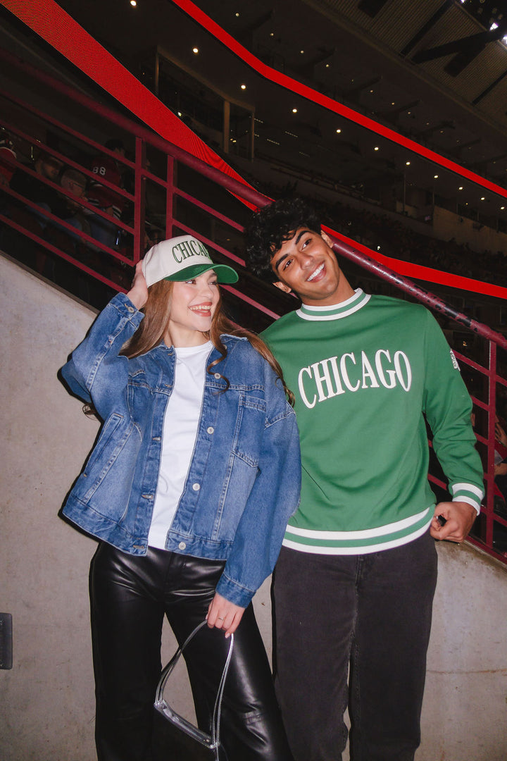 man wearing green Alice & Wonder crewneck sweater with Chicago wordmark graphic and tonal Chicago Blackhawks primary logo on left shoulder 