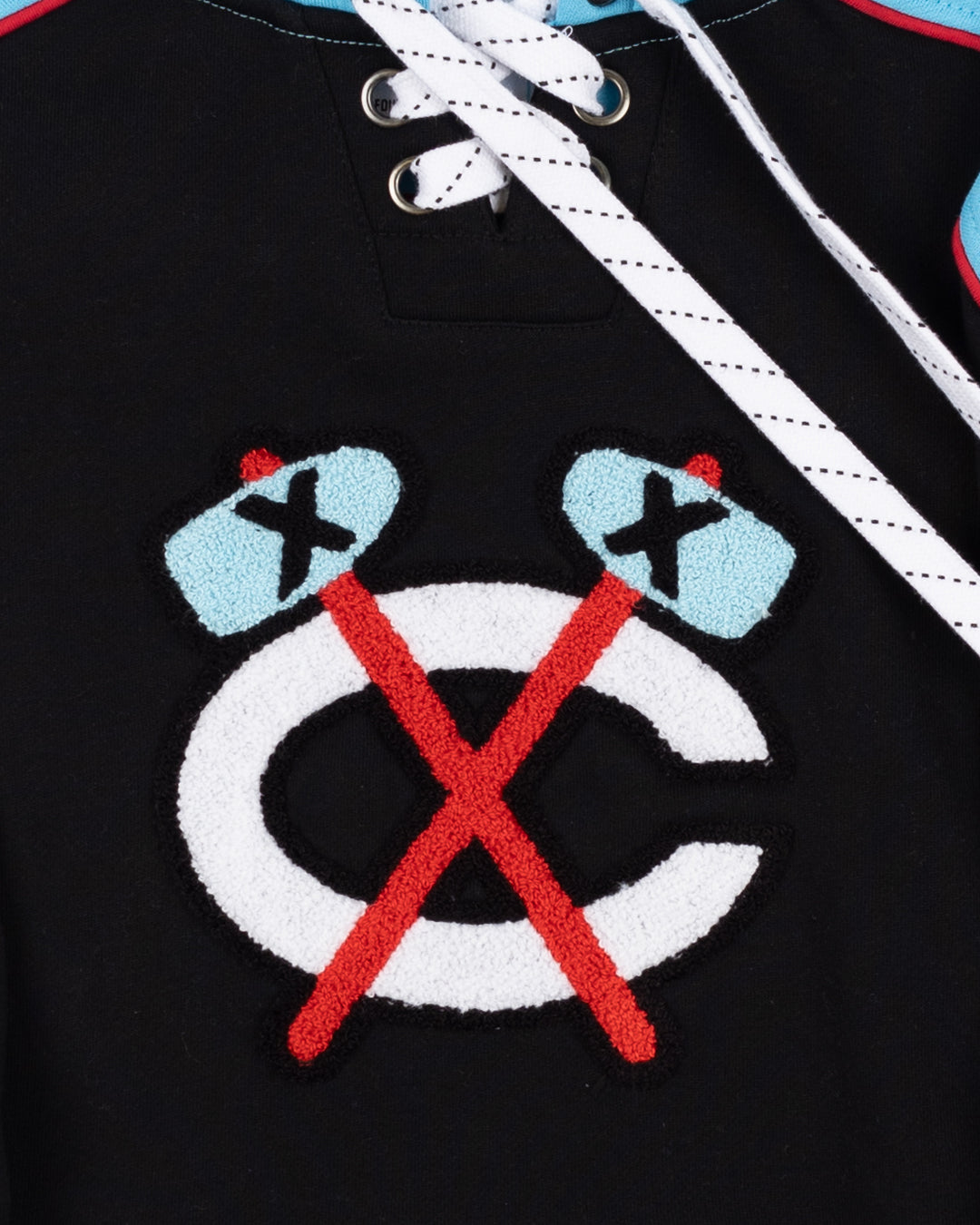 youth black hockey jersey-inspired hoodie with Chicago Blackhawks secondary logo on front, Chicago flag on left shoulder and Four Feathers logo on right shoulder - front detail lay flat