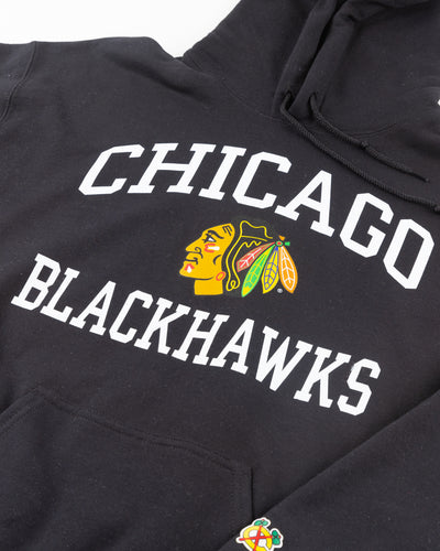 black Chicago Blackhawks hoodie with wordmark and primary logo on chest and secondary logo on left wrist - detail front lay flat