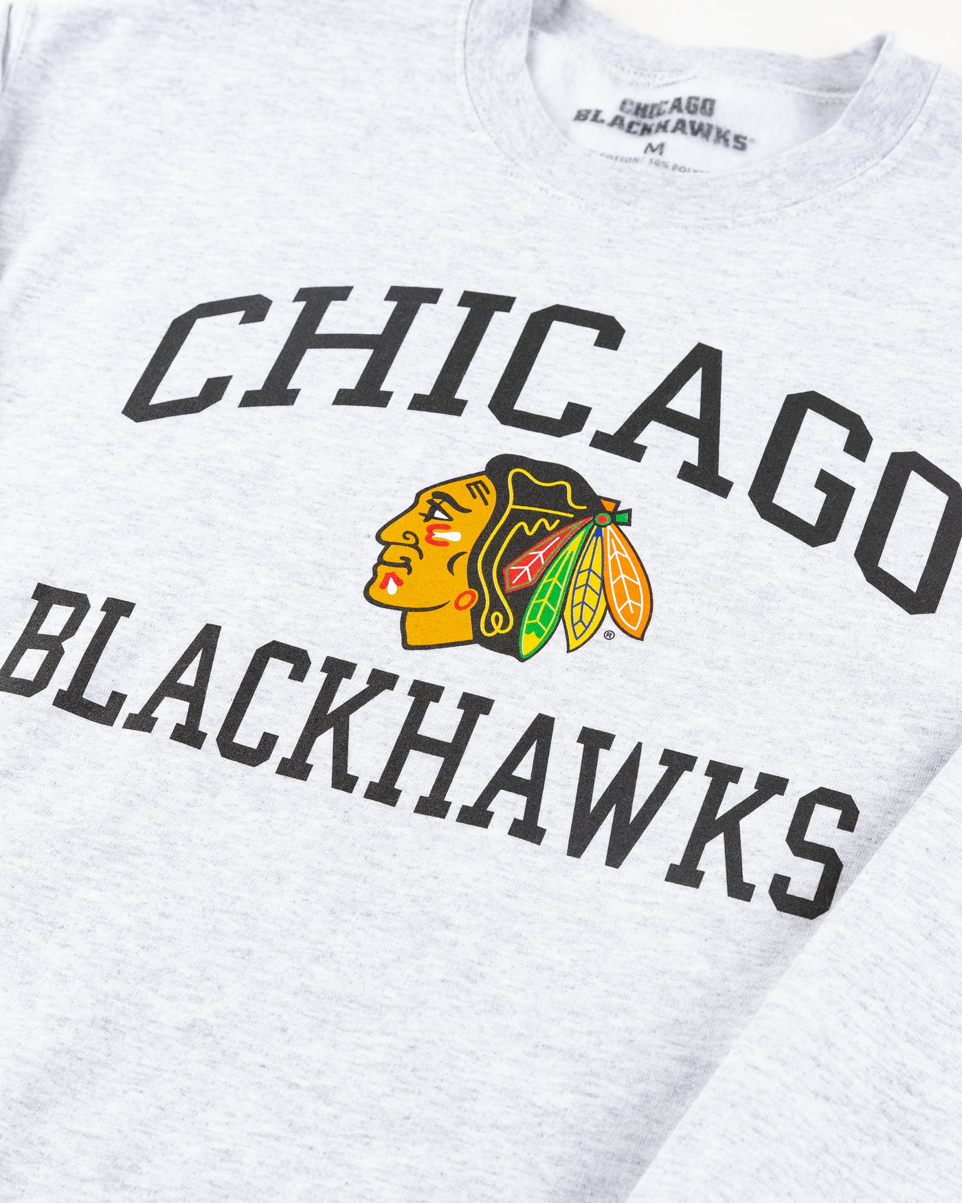 grey Chicago Blackhawks crewneck with wordmark and primary logo on chest and secondary logo on left wrist - detail front lay flat