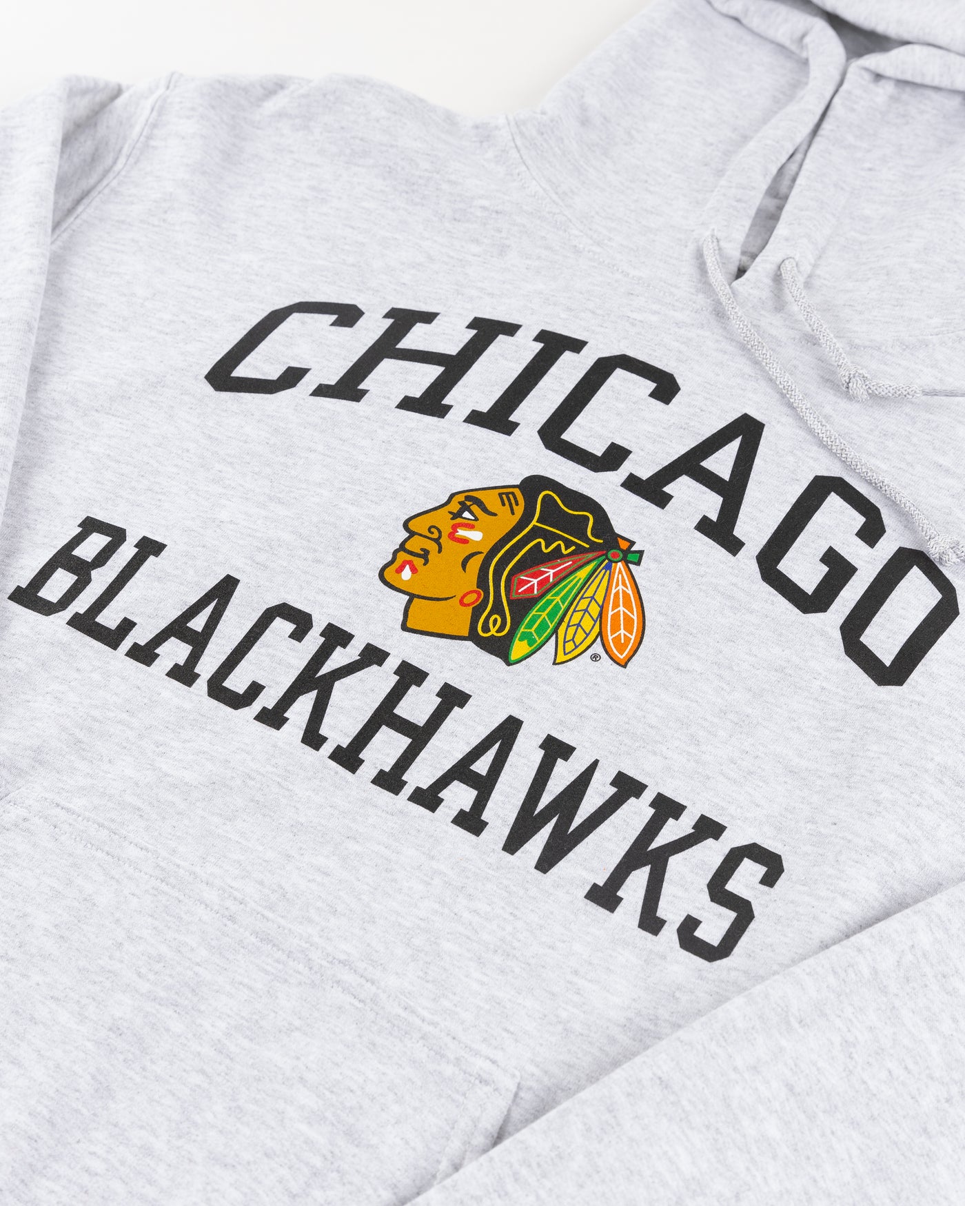 grey Chicago Blackhawks hoodie with wordmark and primary logo on chest and secondary logo on left wrist - detail front lay flat