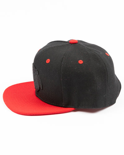 two tone black and red youth snapback cap with Chicago Blackhawks tonal primary logo on front and red wordmark on back - left side lay flat