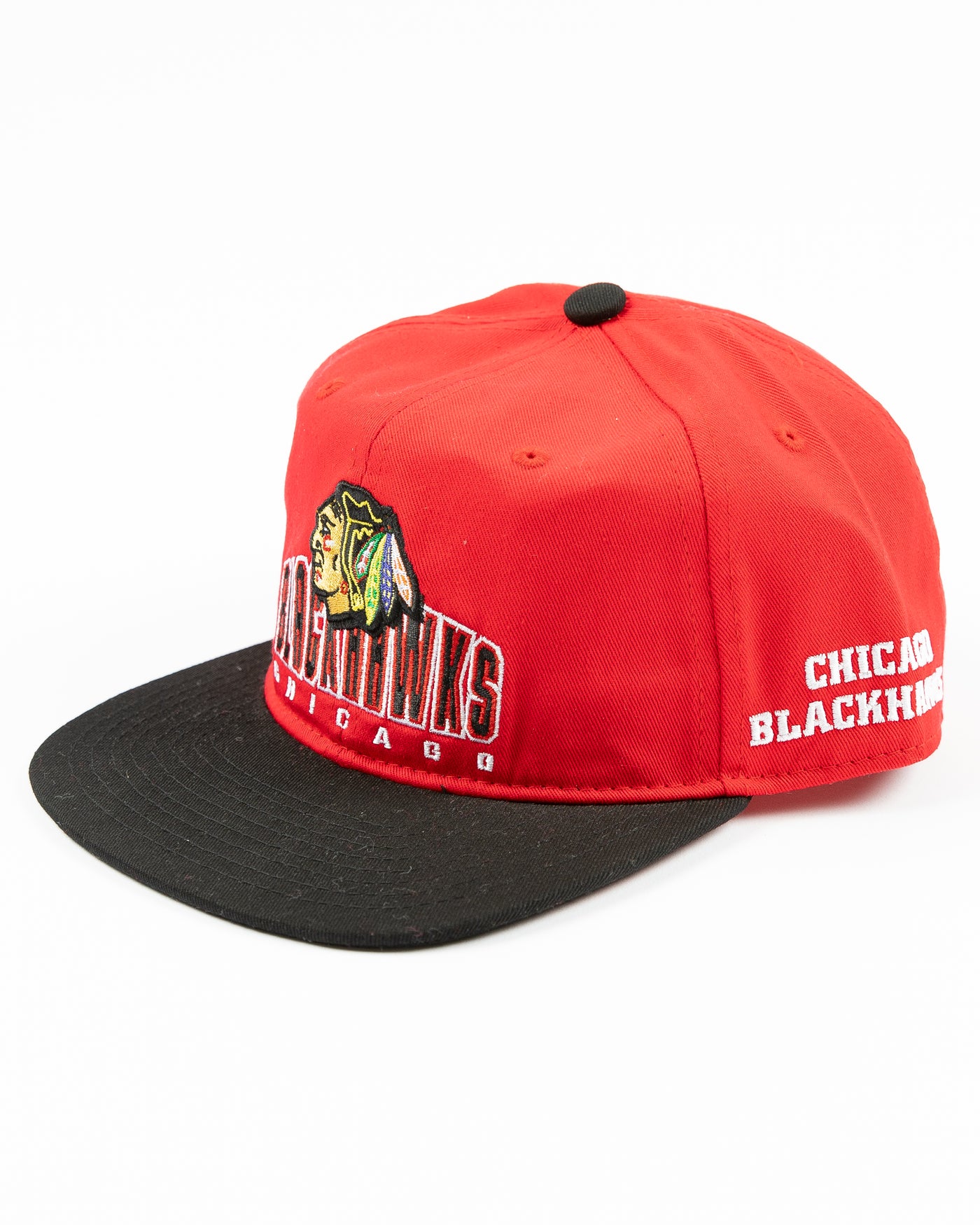 two tone red and black youth snapback cap with Chicago Blackhawks wordmark and primary logo across front - left angle lay flat