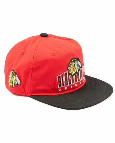two tone red and black youth snapback cap with Chicago Blackhawks wordmark and primary logo across front - right angle lay flat
