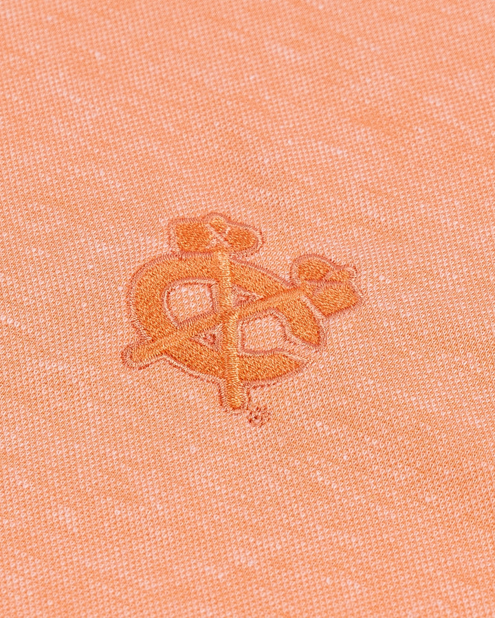 orange TravisMathew polo with Chicago Blackhawks secondary logo embroidered on left chest - detail lay flat