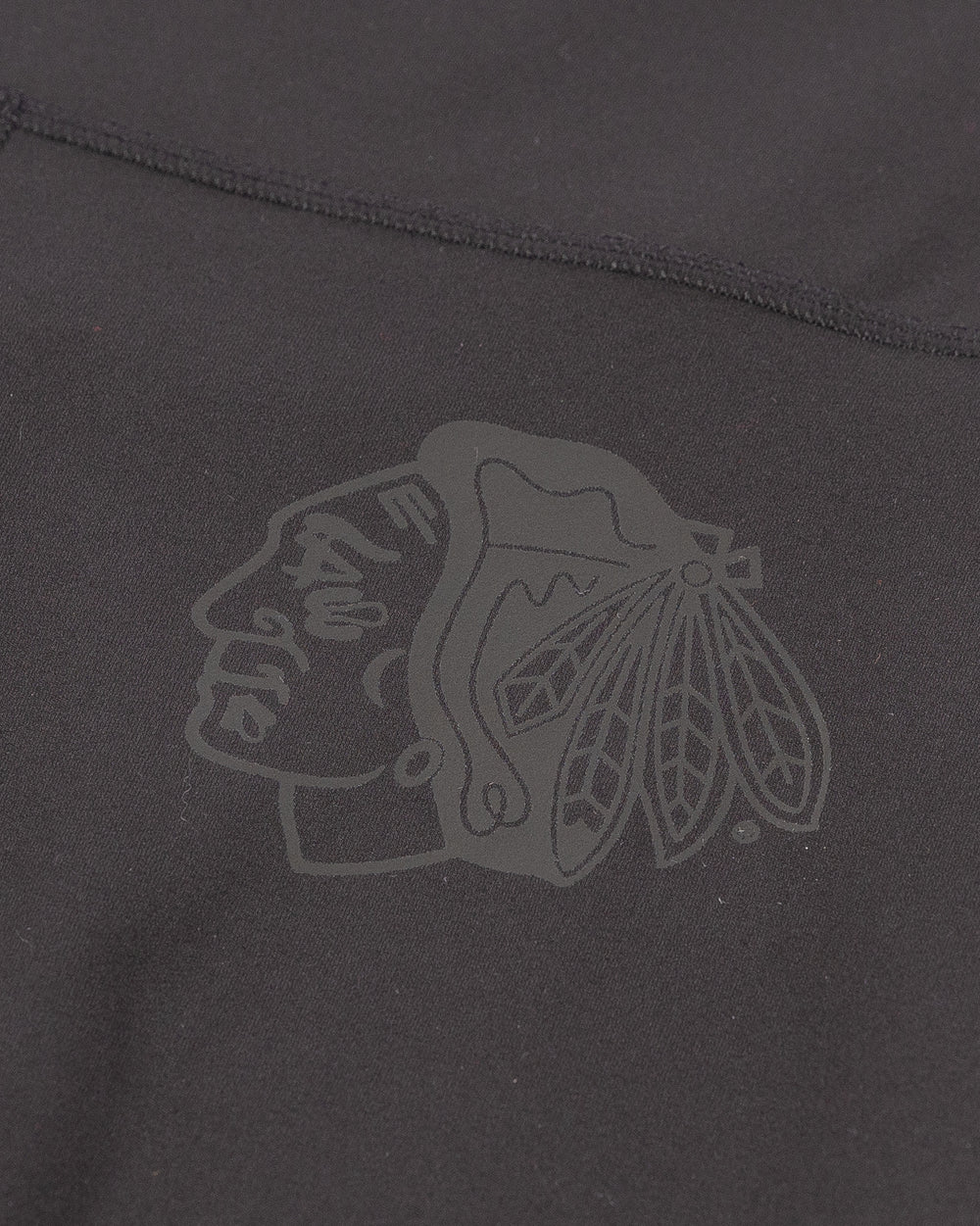 black lululemon yoga pants with subtle flare at hem and tonal Chicago Blackhawks primary logo printed on left leg - detail lay flat