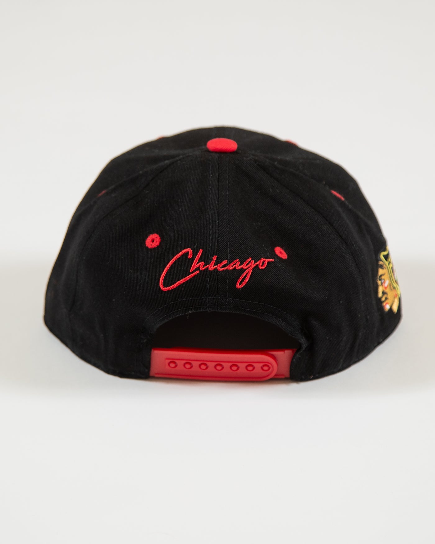 Outerstuff black and red youth snapback with flat brim with Chicago Blackhawks wordmark and primary logo with graffiti inspired design - back angle lay flat