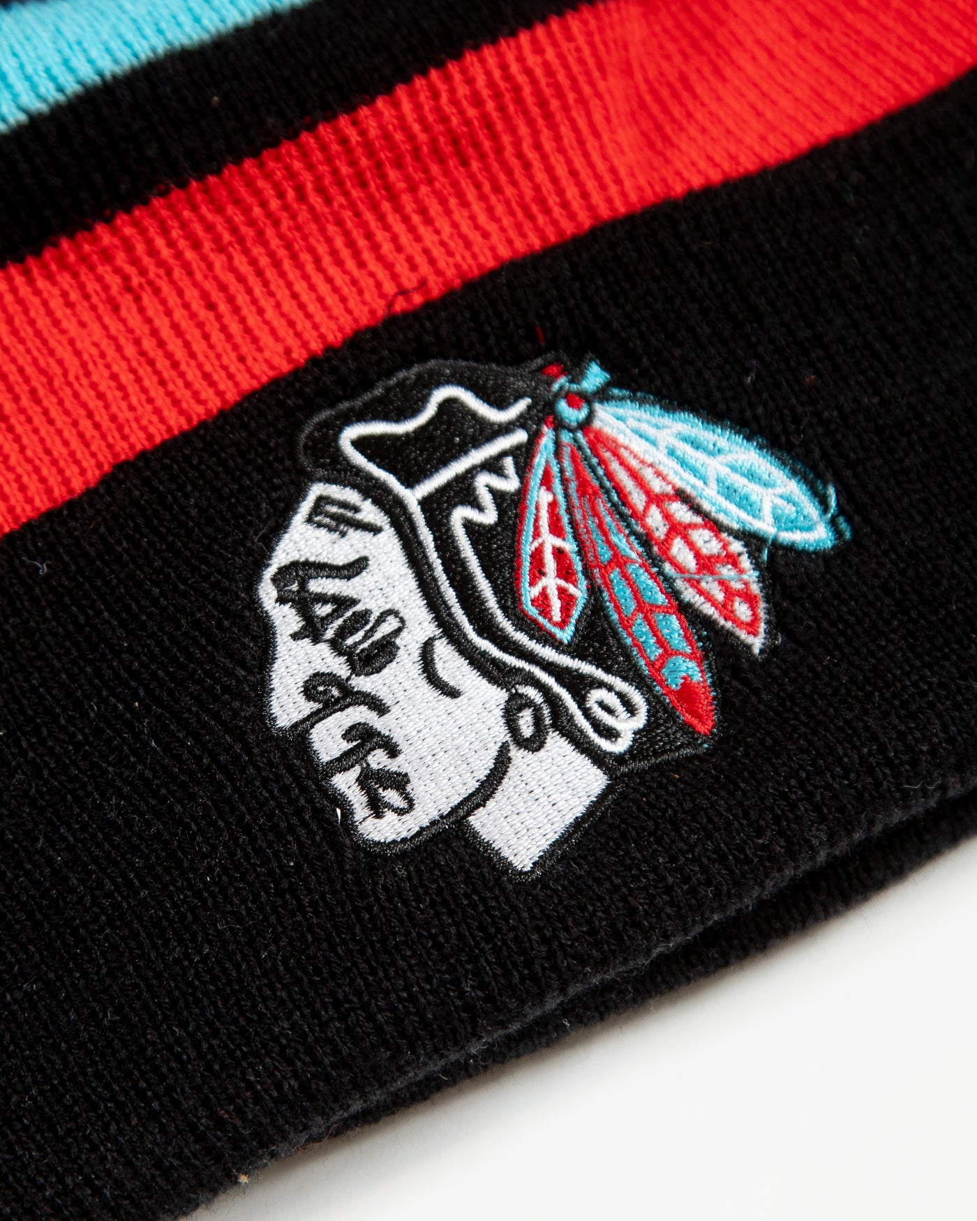 Four Stars knit hat with stripes and pom and Chicago Blackhawks primary logo in Chicago flag inspired colorway - detail logo angle lay flat