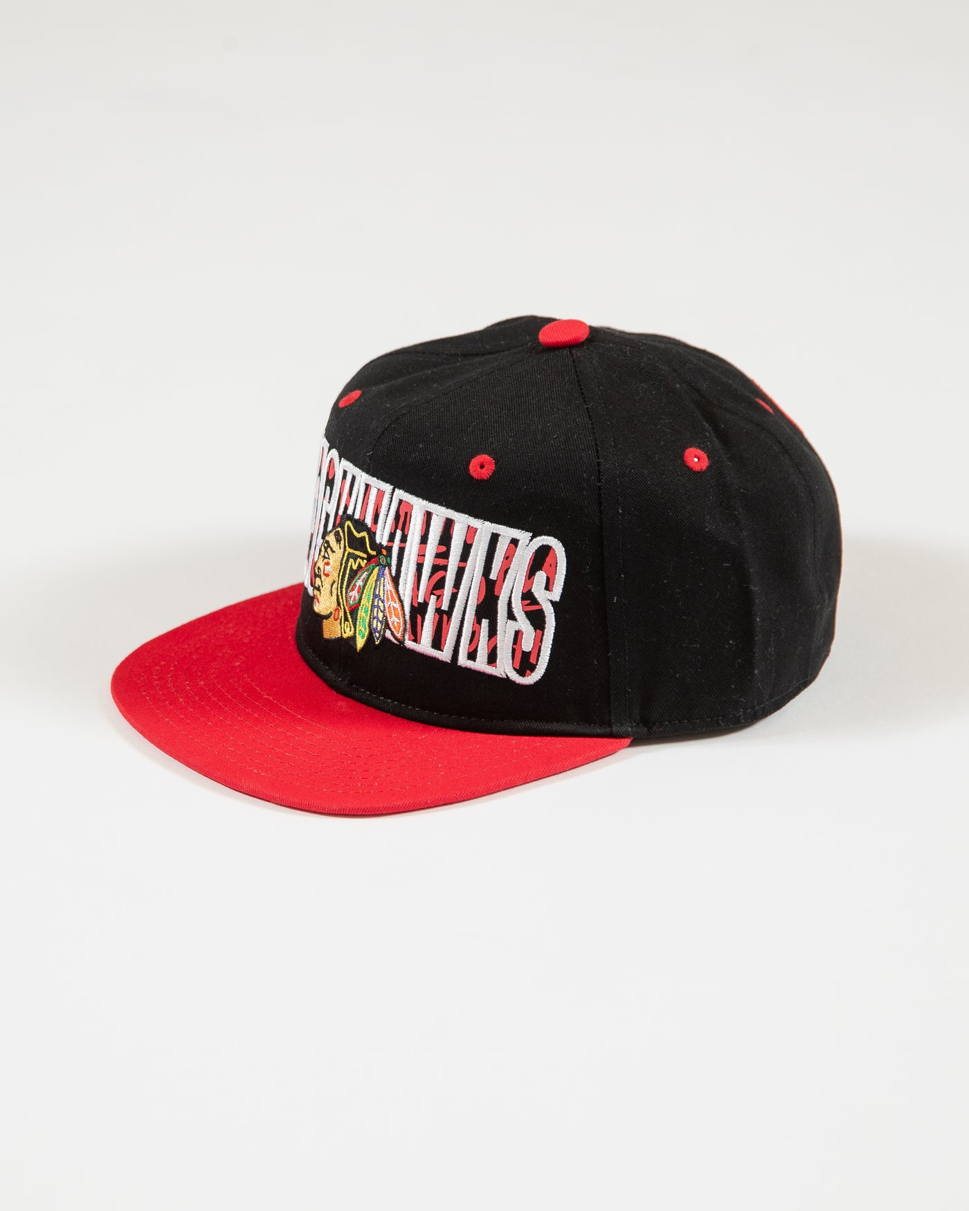 Outerstuff black and red youth snapback with flat brim with Chicago Blackhawks wordmark and primary logo with graffiti inspired design - left angle lay flat