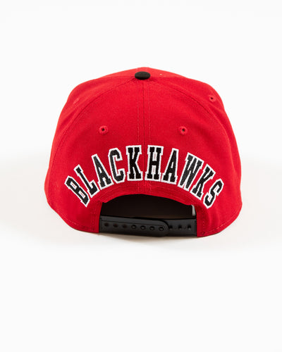 Red and black New Era snapback with Chicago Blackhawks primary logo and secondary logo embroidered on front - back lay flat