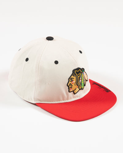 Outerstuff two-tone youth hat in bone and red with Chicago Blackhawks primary logo embroidered on front and Blackhawks script on left panel - right angle lay flat