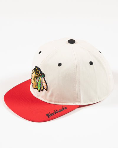 Outerstuff two-tone youth hat in bone and red with Chicago Blackhawks primary logo embroidered on front and Blackhawks script on left panel -left angle lay flat