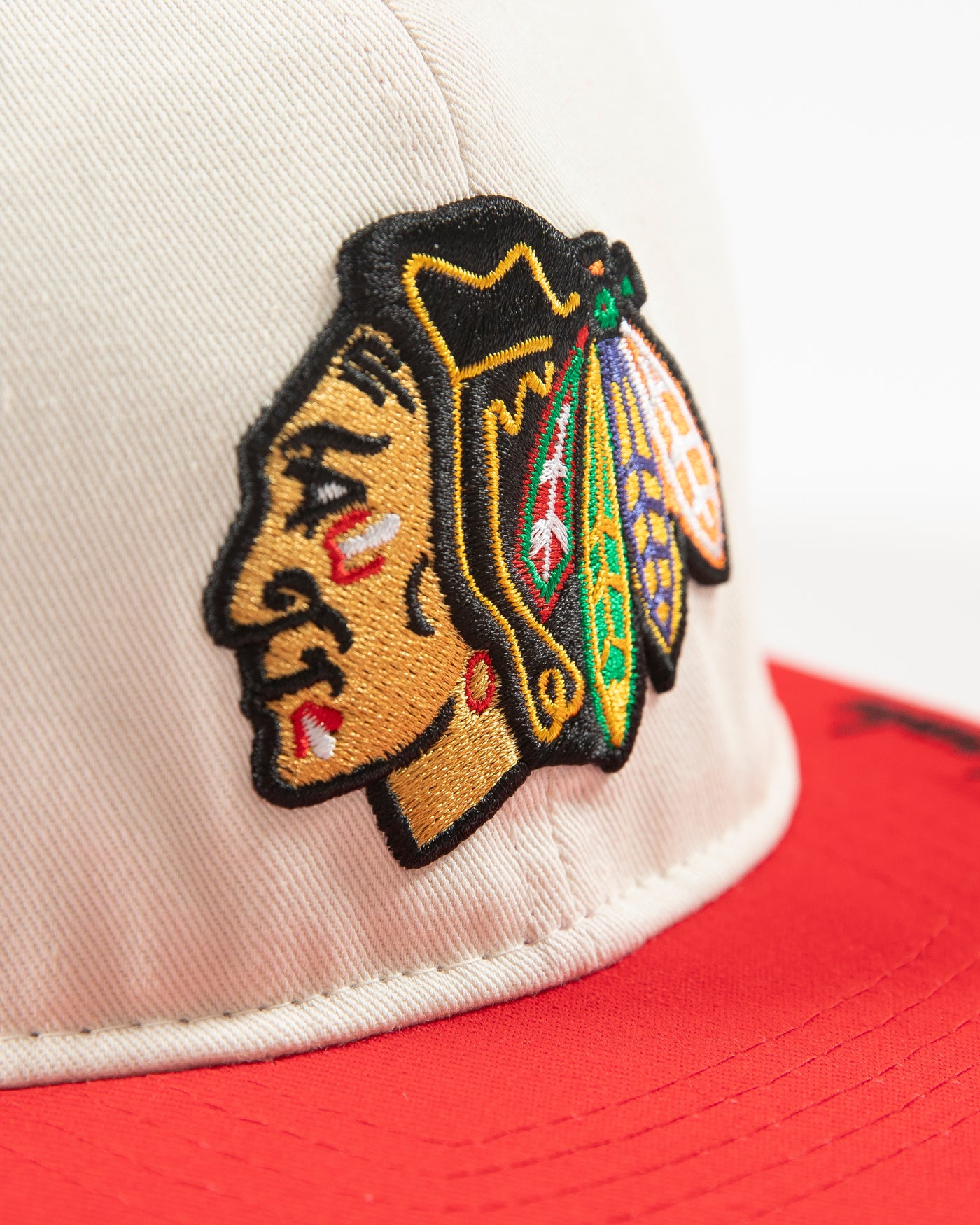 Outerstuff two-tone youth hat in bone and red with Chicago Blackhawks primary logo embroidered on front and Blackhawks script on left panel - detail lay flat