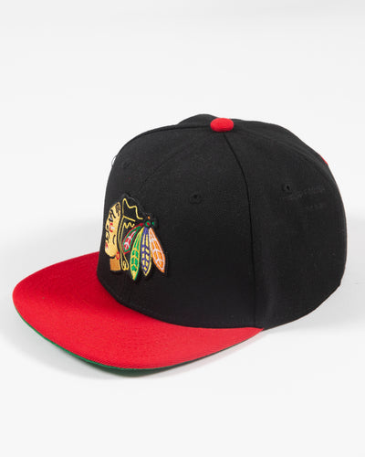 black and red Mitchell & Ness youth snapback with Chicago Blackhawks primary logo embroidered on front - left angle lay flat