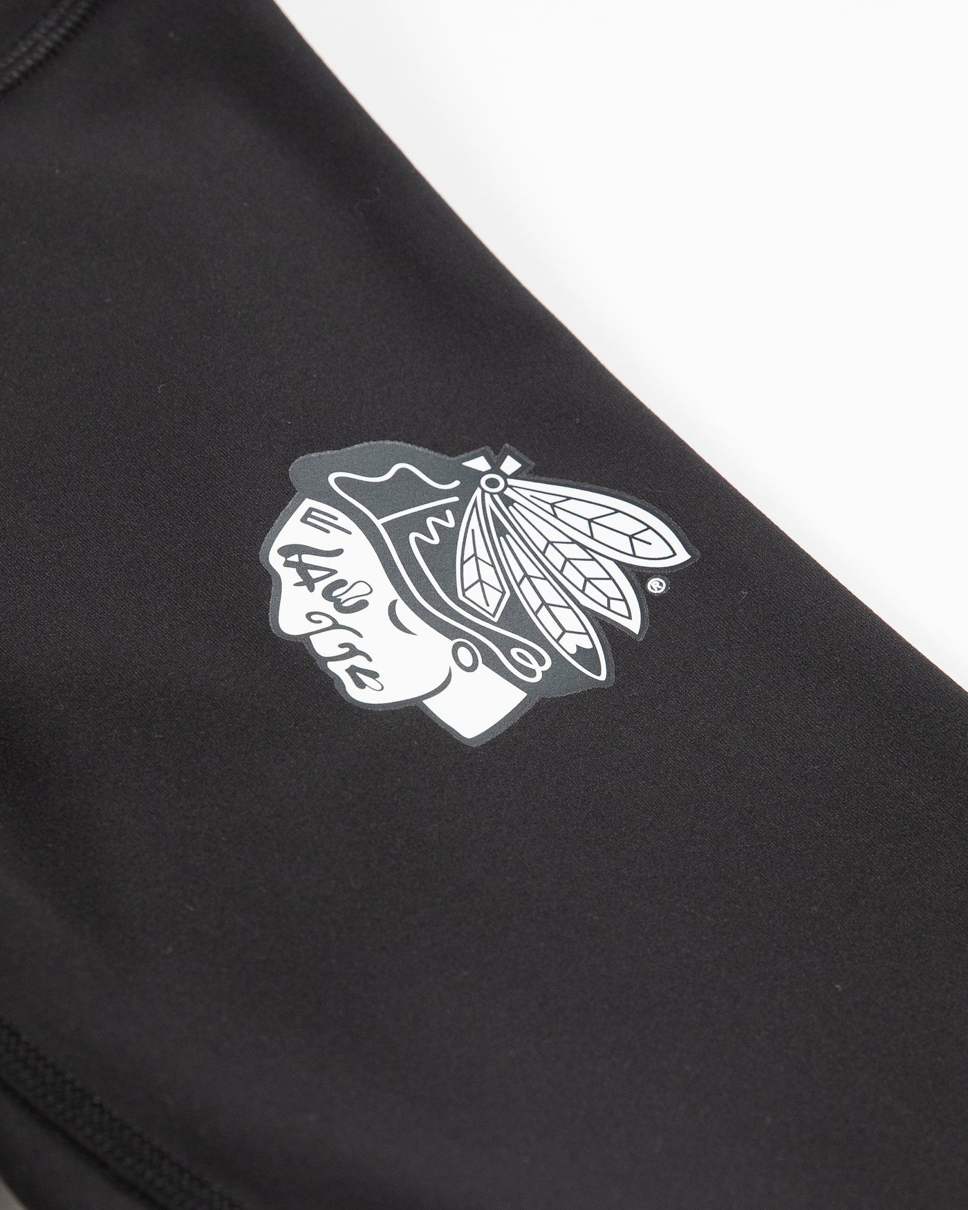 Black lululemon leggings with white tonal Chicago Blackhawks primary logo on left thigh - detail lay flat