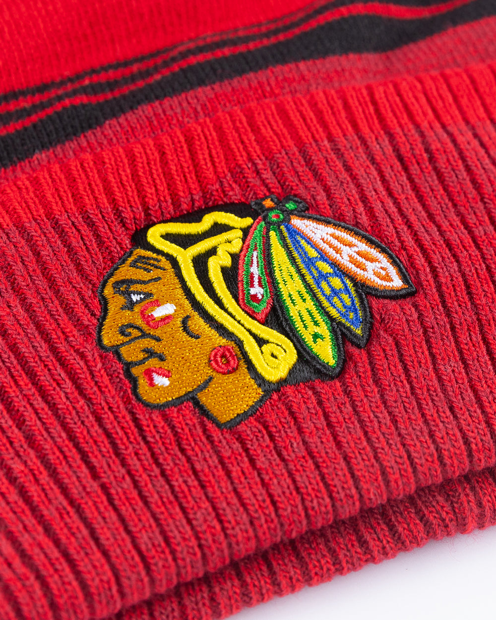 red and black '47 brand knit beanie with red pom and Chicago Blackhawks primary logo embroidered on front cuff - detail lay flat